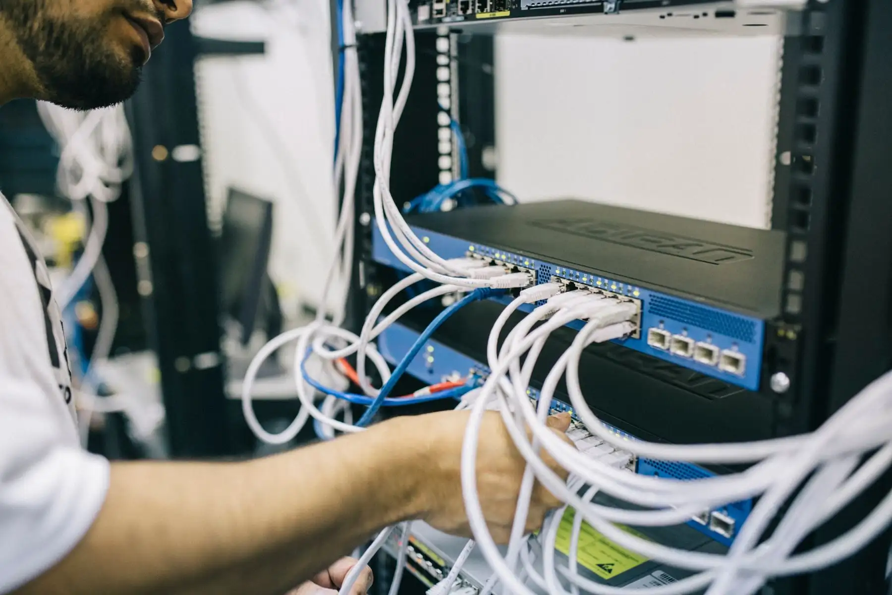 IT-Techniker steckt Netzwerkkabel in einen Switch in einem Serverschrank.