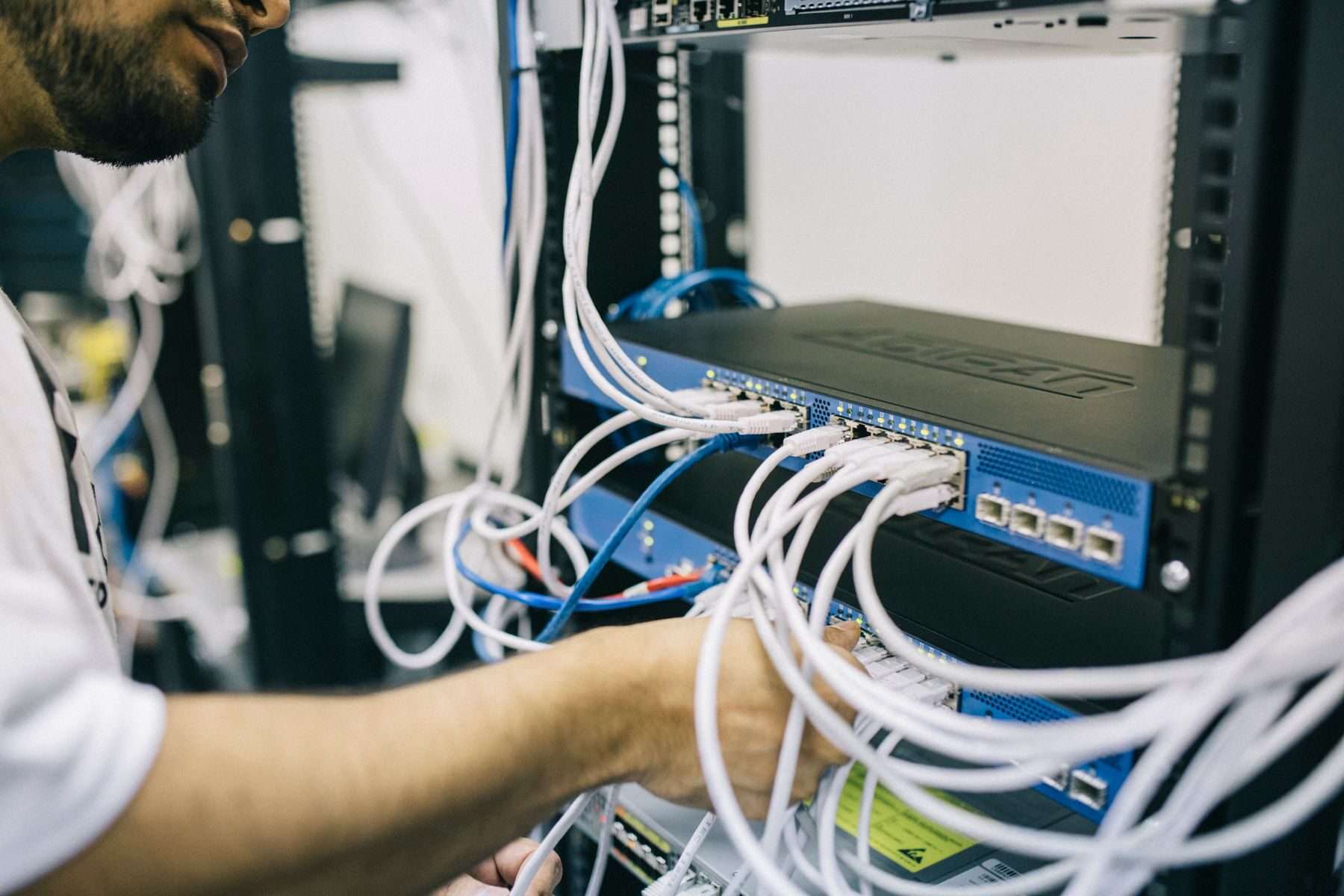 IT-Techniker steckt Netzwerkkabel in einen Switch in einem Serverschrank.