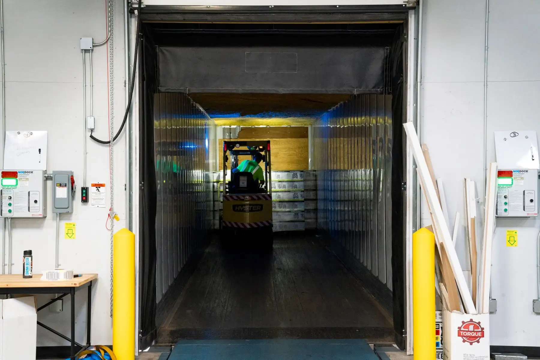 Blick vom Ladetor in einen Lkw-Auflieger, in dem ein Gabelstapler Paletten verlädt.